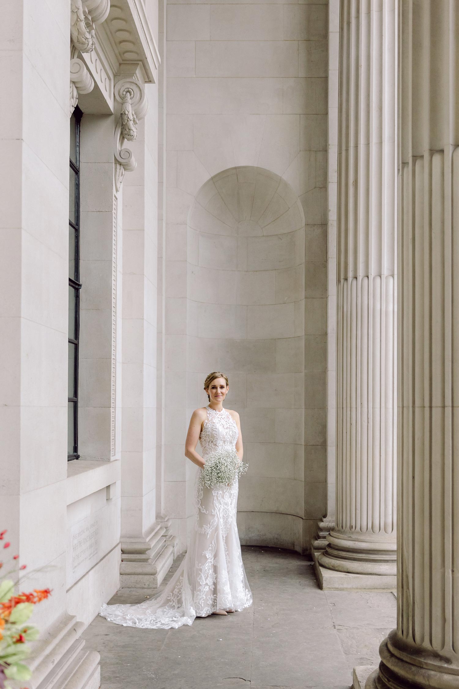 A bride stands alone outside The Old Marylebone Town Hall at her London micro wedding
